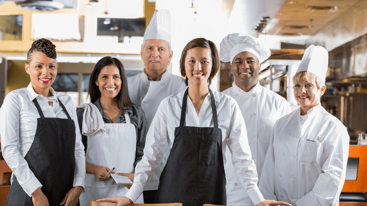 A team of hotel and restaurant staff in uniform standing together in a kitchen
